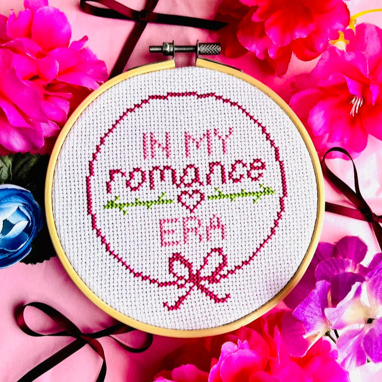 Cross-stitched hoop with 'In My Romance Era' text surrounded by pink flowers
