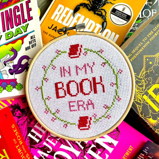 Cross Stitch hoop with 'In my book era' design on a colourful background of books.