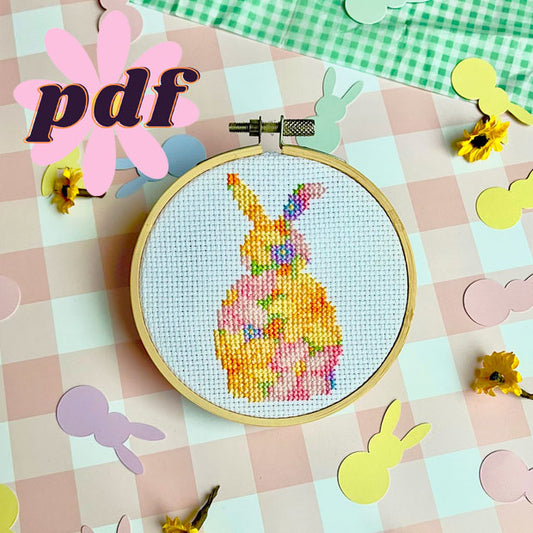 A small cross stitch depicting a floral bunny design in a hoop, surrounded by pastel rabbit cutouts